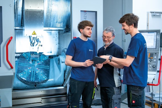 Three employees discussing in the production area of NOVOMATIC